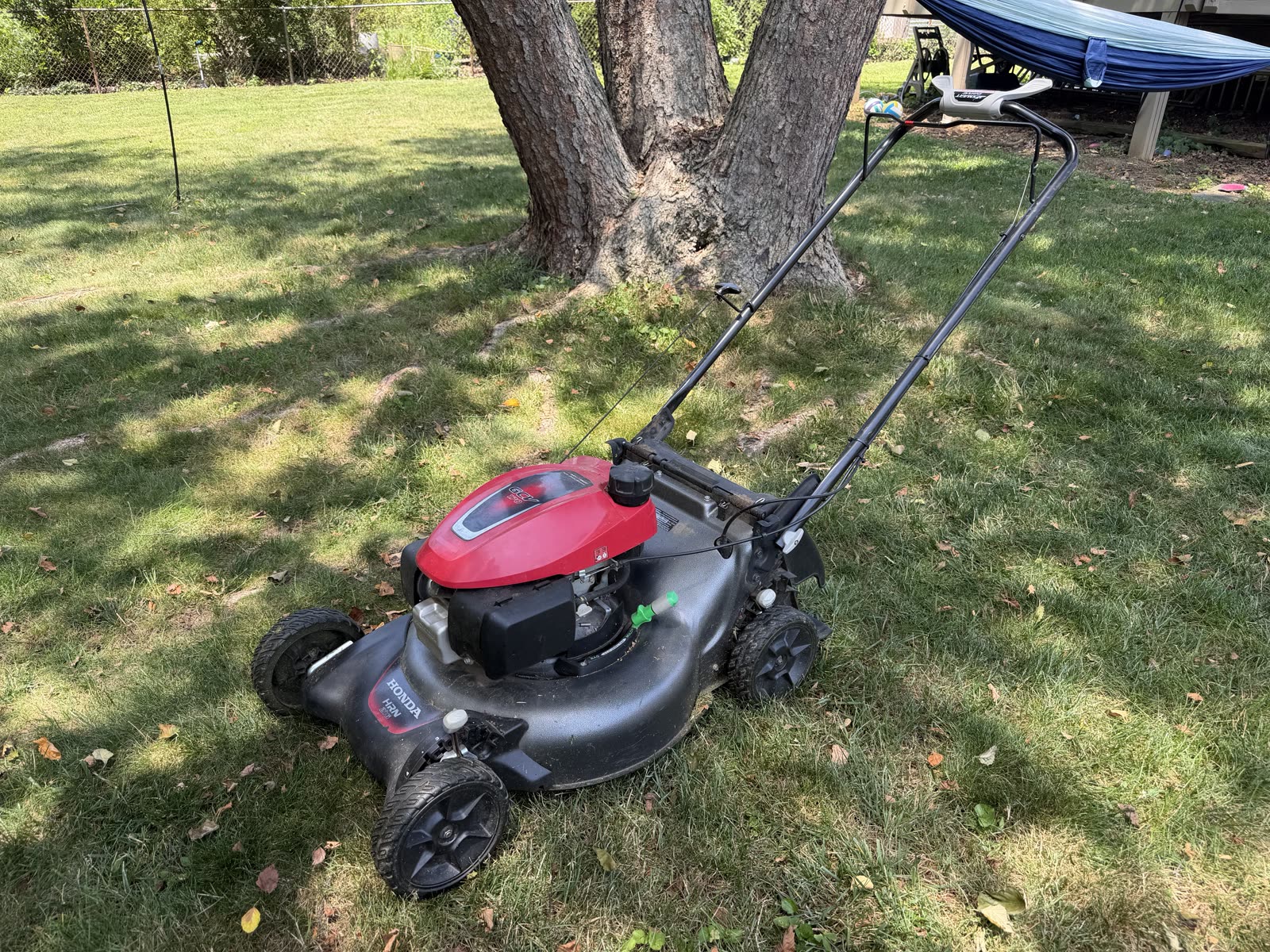 The used Honda HRN216 mower sitting in the yard
