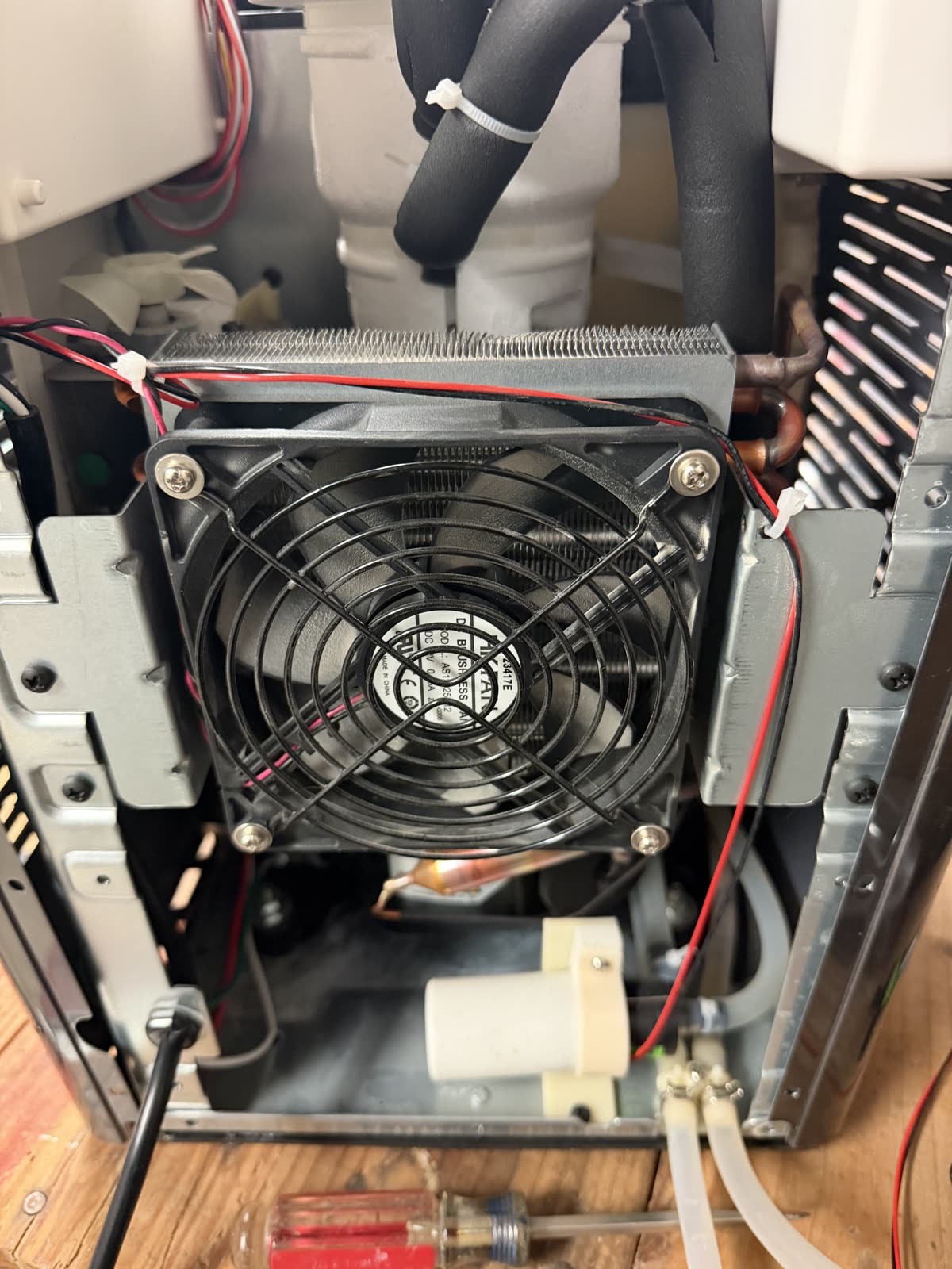 Opal with the back panel removed, showing the condenser fan and the water pump