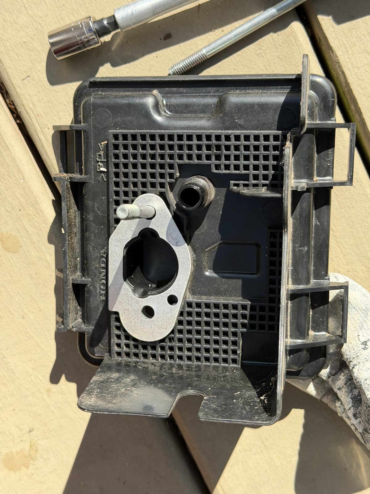 The air cleaner housing and metal insulator plate laid out on the deck