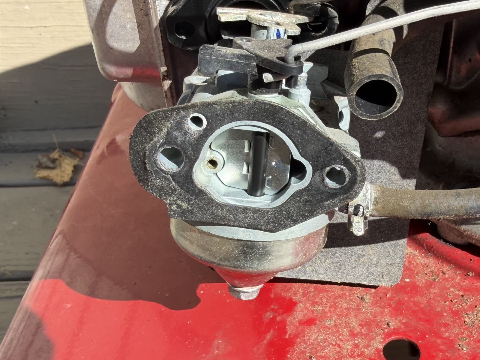 The new genuine Honda carburetor installed on the engine, gasket face visible